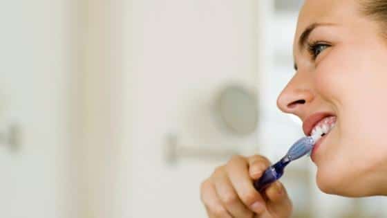 Woman brushing her teeth as a trick to lose weight.